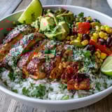 The Cajun Chicken Bowl features golden, spice-crusted chicken over colorful rice and vegetables, with lime wedges for a fresh Southern-inspired finish.