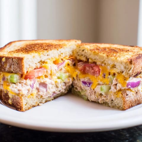 A close-up of a Spicy Tuna Melt sandwich, featuring creamy tuna salad and gooey cheddar cheese.  