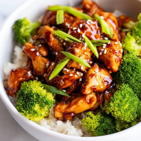 Aerial view of a homemade Sweet Chili Chicken Bowl featuring tender chicken glazed in a sweet chili sauce, served over white rice with broccoli florets.