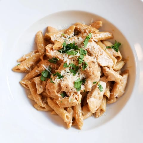 Steaming bowl of Honey Chipotle Chicken Pasta featuring tender chicken and penne in a rich, smoky sweet sauce with a fresh lime wedge on the side.