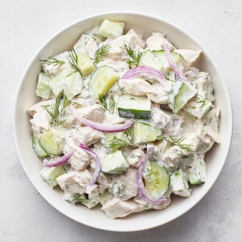 Close-up of a fork lifting a bite of creamy cucumber chicken salad with tender chicken, crisp cucumber, and creamy dill yogurt dressing.