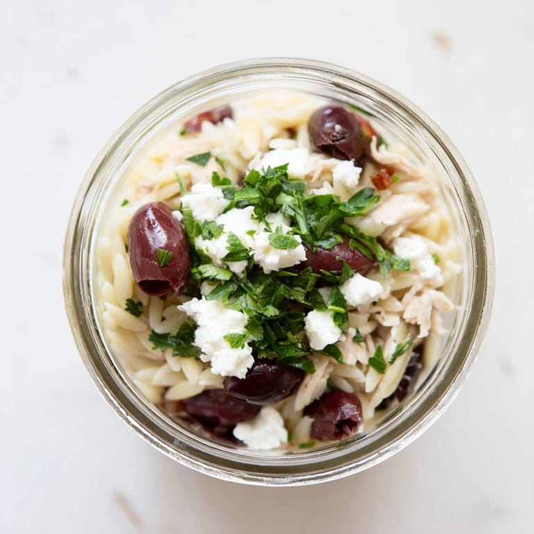 Delicious Greek Pasta Chicken Salad Jar ready to shake, featuring orzo, juicy chicken, Kalamata olives, and tangy oregano dressing for Mediterranean-inspired lunches.