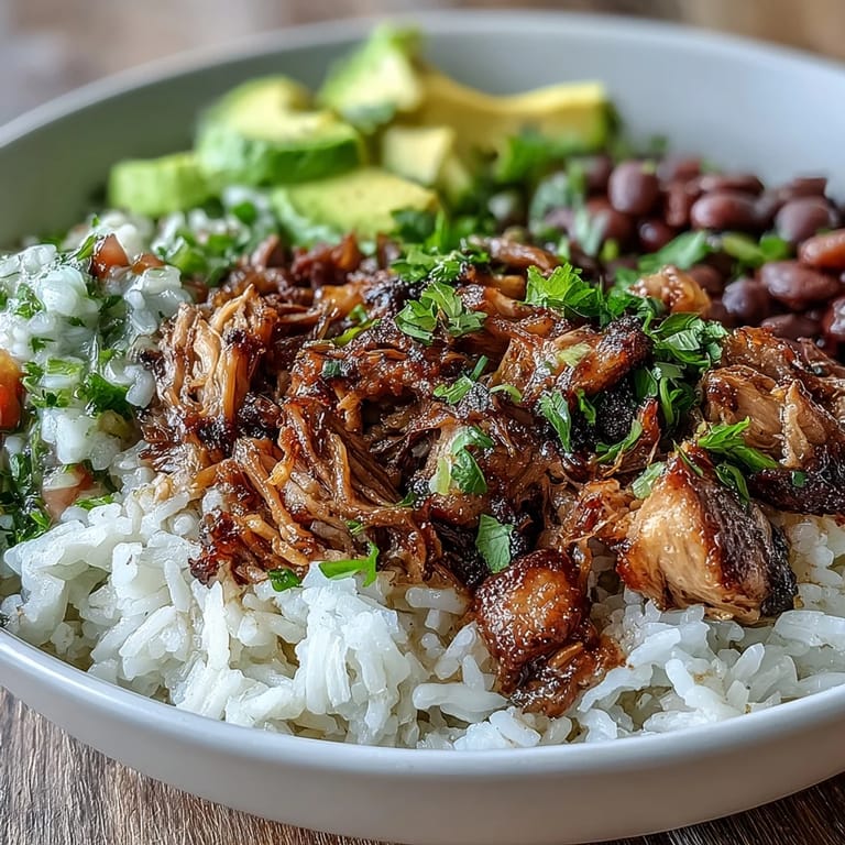 A hearty Mexican-style carnitas bowl with lime wedges, cilantro, and creamy avocado for a vibrant meal.