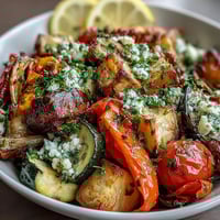 Roasted Mediterranean Greek Vegetables sizzling on a baking sheet with caramelized edges and fresh herbs.