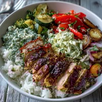 Juicy BBQ chicken slices rest on fluffy rice with crunchy coleslaw and roasted vegetables in this BBQ Chicken Bowl.
