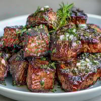 Juicy steak bites sizzling in a cast iron skillet, seared with garlic and fresh herbs for a flavorful one-pan dinner.